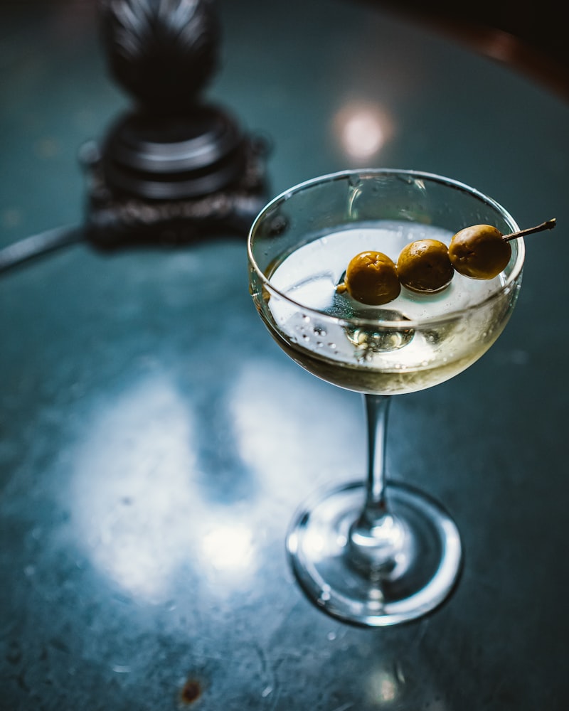 Deep red stirred rye cocktail in a coupe with a brandied cherry